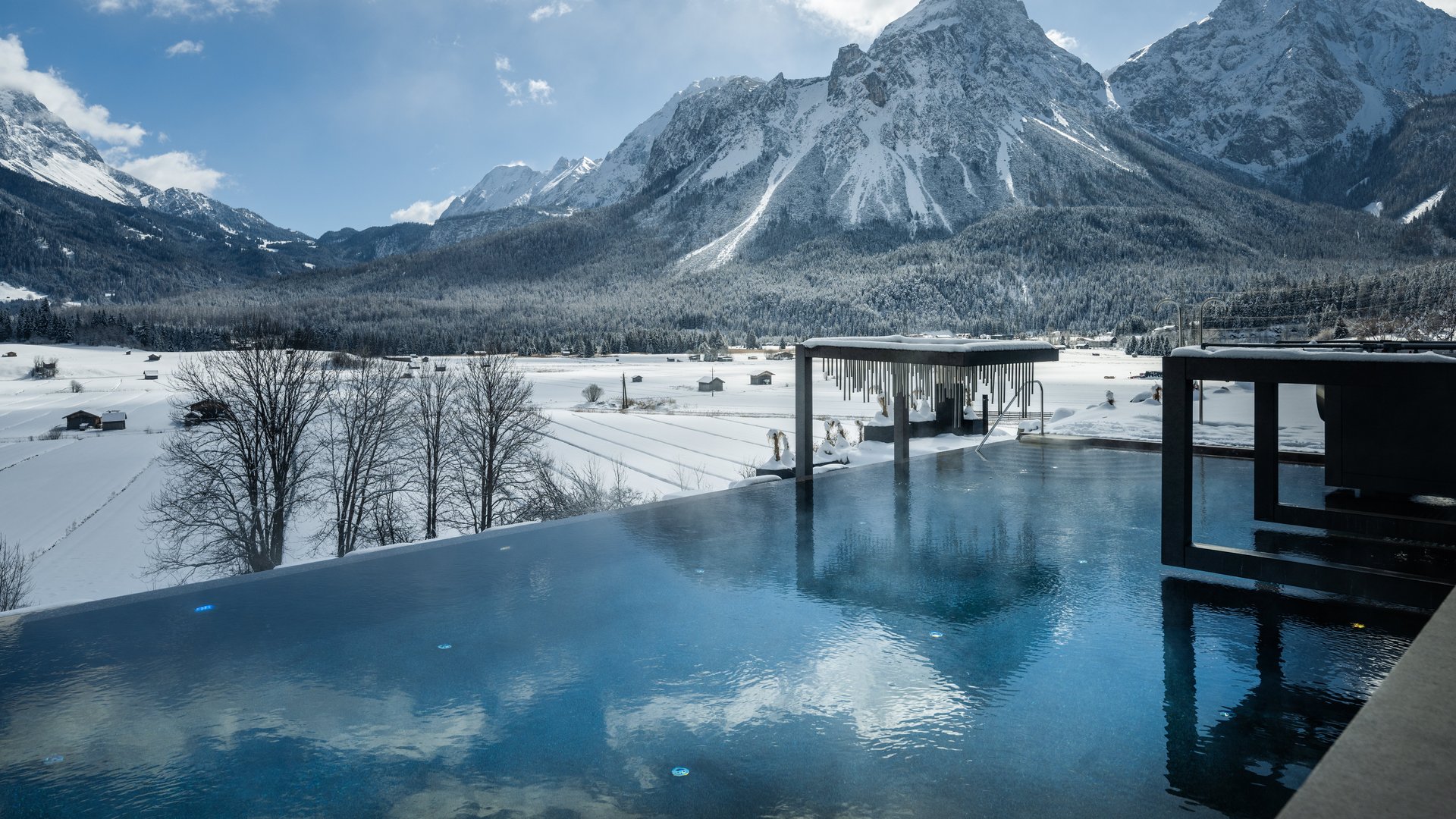 Infinity pool with snowy mountains and blue sky